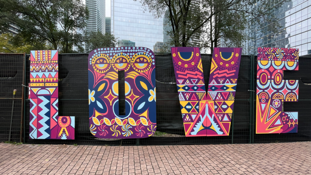 A mural that spells out LOVE and has patterns in blue, pink, yellow, and purple.